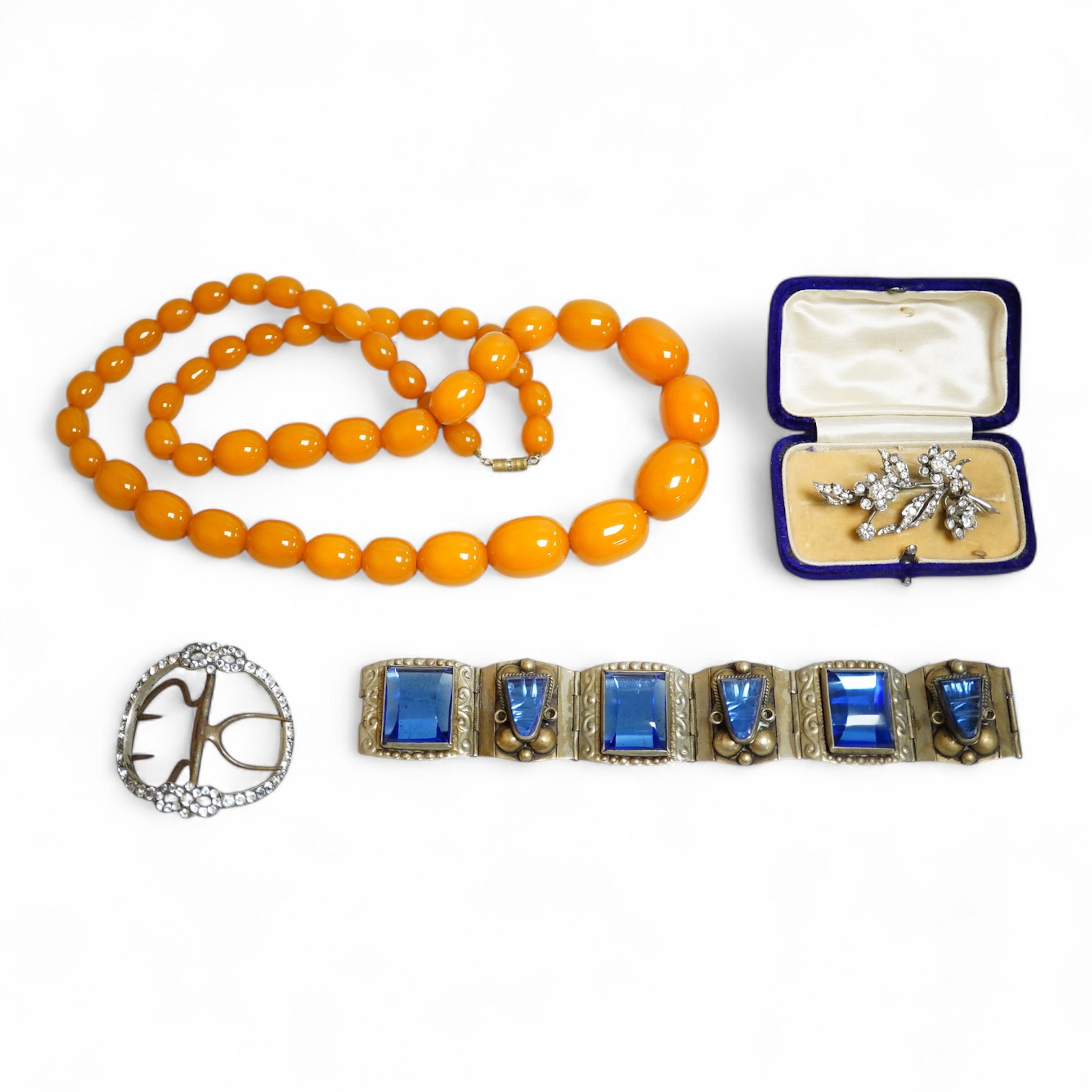 A group of antique and later jewellery inc. cased paste set spray brooch, a Mexican paste set brooch, a paste set shoe buckle and a pressed amber necklace.